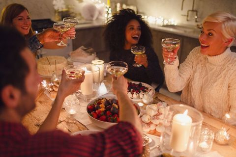 Enthousiaste vrienden die champagneglazen roosteren bij het diner bij kaarslicht