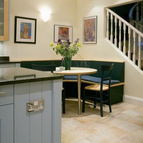 hoekbank aan tafel in moderne keuken met lichtblauw meubel en trap naar bovenverdieping