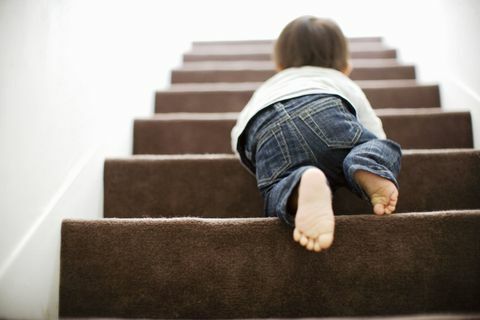 Baby klimt de trap op door te kruipen