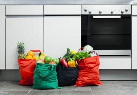 Herbruikbare boodschappentassen gevuld met fruit en groenten in een keuken.