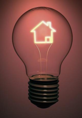 Een enkele huislamp bevat een gloeiende fillament in de vorm van een huis die energie, elektriciteit en groene problemen aangeeft