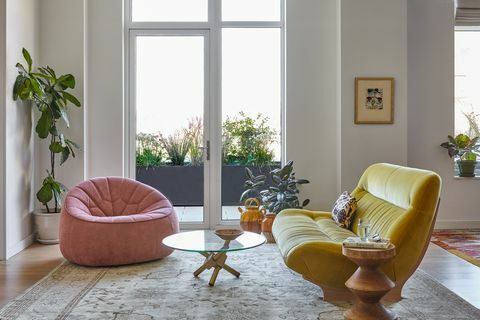 woonkamer met roze stoel en gele bank
