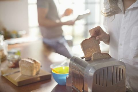 Vrouw die brood in de broodrooster zet