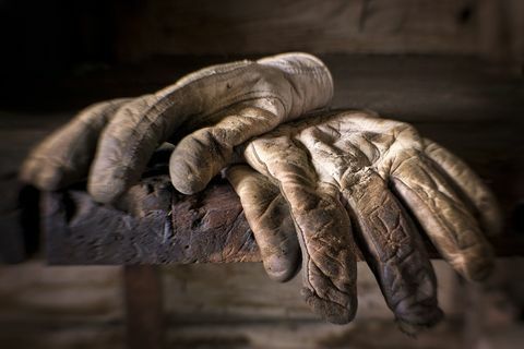 Goed gedragen, vuile en olieachtige werkhandschoenen bovenop een oude werkbank.