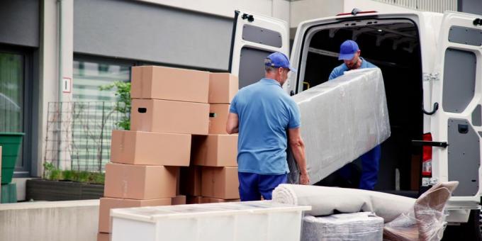 mannelijke werknemers in blauw uniform die meubels lossen