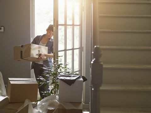 en vrouw die een verpakkingsdoos naar haar nieuwe huis draagt