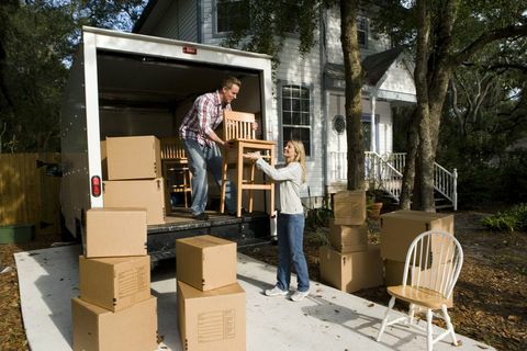 Tussentijdse volwassen paar lossen stoelen en kartonnen dozen van de verhuiswagen