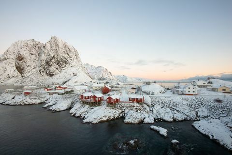 Rood vissershuisdorp onder de sneeuw met bergmening in Lofoten-eiland Hamnoy Noorwegen