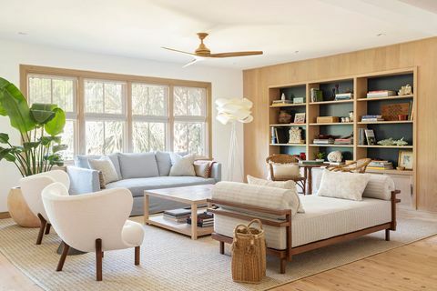 zitkamer, bibliotheek boekenkast, witte chaise longue met houten armen, blauwe slaapbank, witte fauteuils