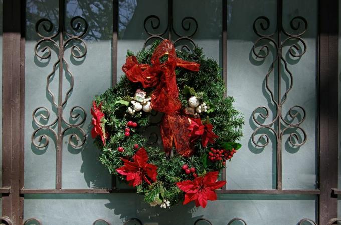 kerstkrans op een elegante smeedijzeren en matglazen voordeur