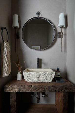 een wastafel in de badkamer met een ronde spiegel