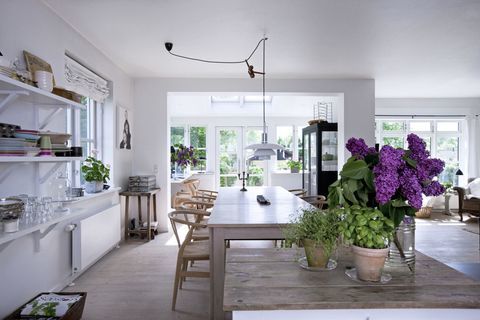 Lichte, vriendelijke en gezellige woonkamer in Scandinavische stijl. Een luchtige keuken met witte muren en deuren; Een eiland met bloemen.