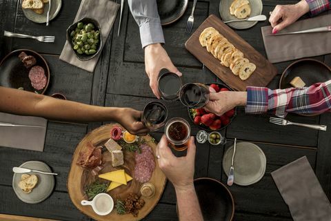 Bovenaanzicht van vrienden die een maaltijd delen: vrienden die vleeswaren en tapas delen met wijn en bier.