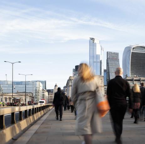 uk, londen, achteraanzicht van zakenlieden en -vrouwen die naar het werk lopen via london bridge met uitzicht op het financiële district