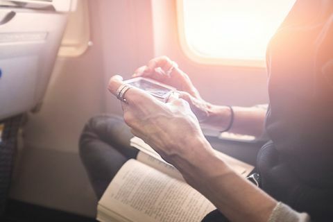Persoon speelspel op smartphone aan boord van vliegtuig