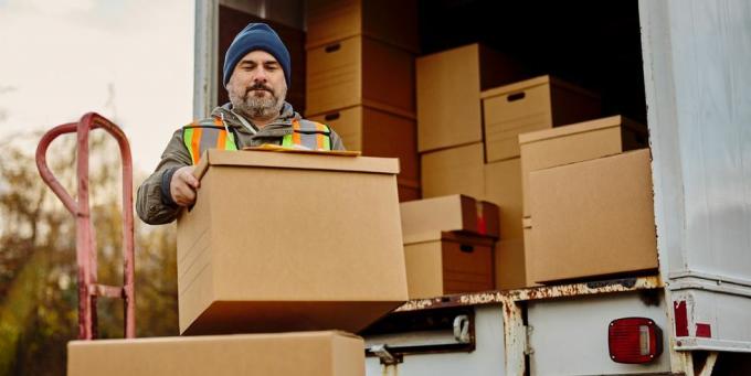 mannelijke werknemer lossen kartonnen dozen uit bestelwagen