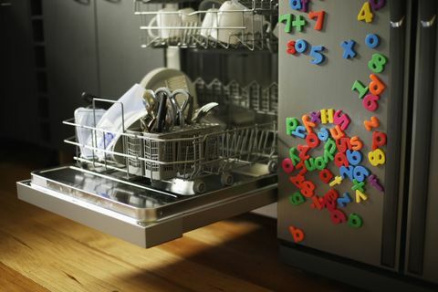 Vaatwasmachine met open lade naast koelkast bedekt met koelkastmagneten voor kinderen