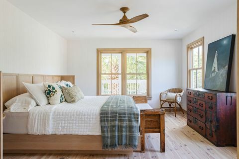 slaapkamer, houten bedframe, rood oud dressoir met kunstwerk erop