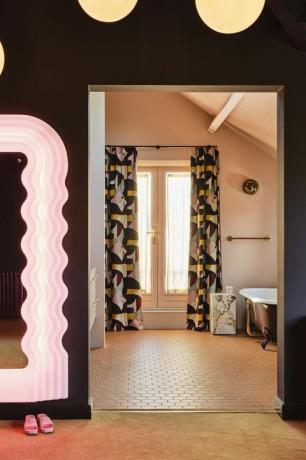 eigen badkamer. bijpassende gordijnen, een open deuropening en een gedempt karamel kleurenschema verbinden de twee kamers spiegel vintage ettore sottsass tegels winckelmans