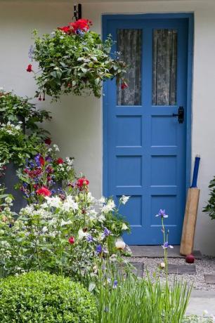 Blauwe voordeur met cricket bat en plantenbakken