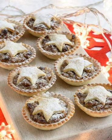 Gebakken fijngehakte pastei voor Kerstmis op witgekalkt bord met dennennaald en decoraties